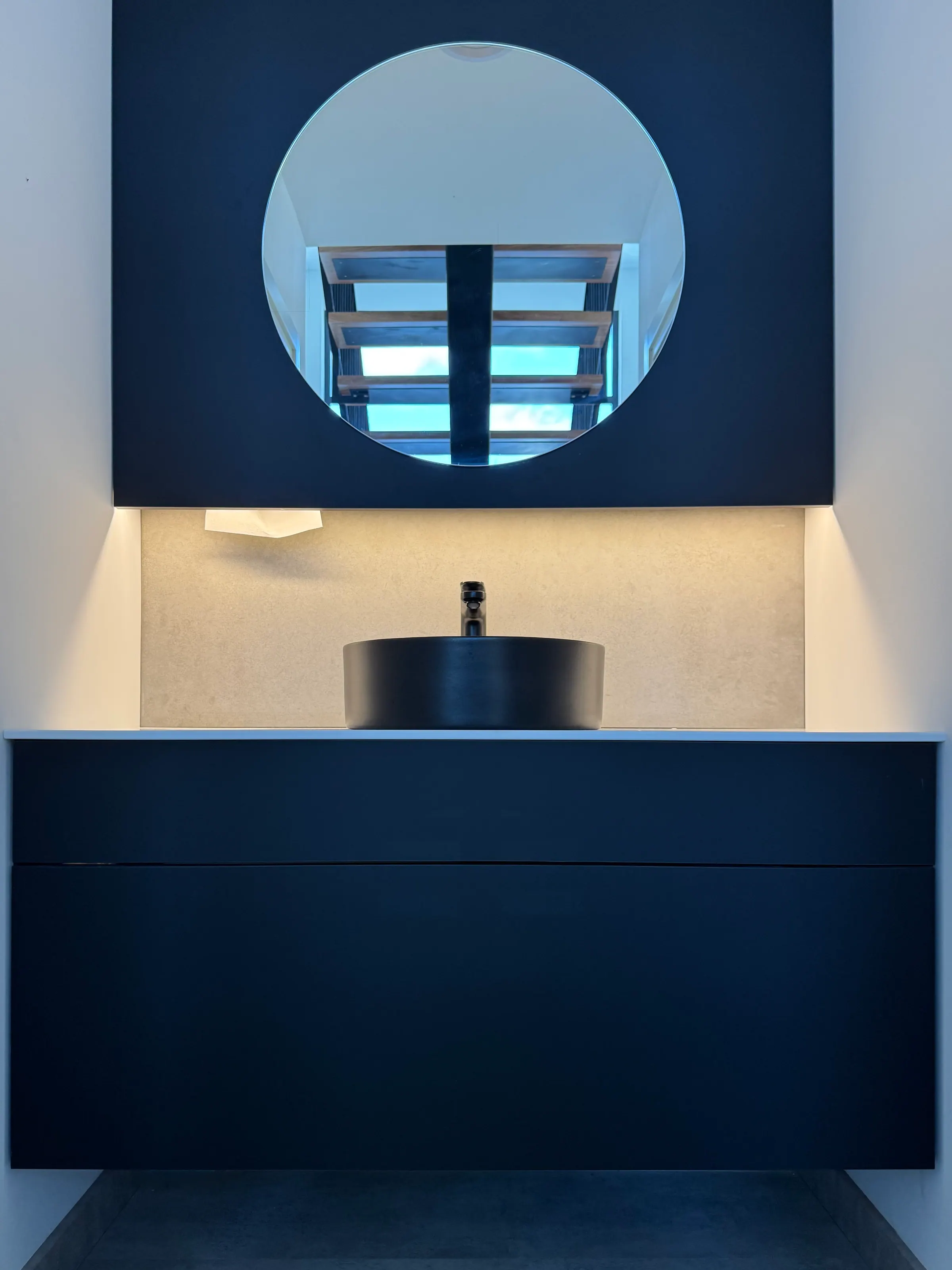 Mueble de baño a medida en azul oscuro con lavabo y espejo redondo iluminado