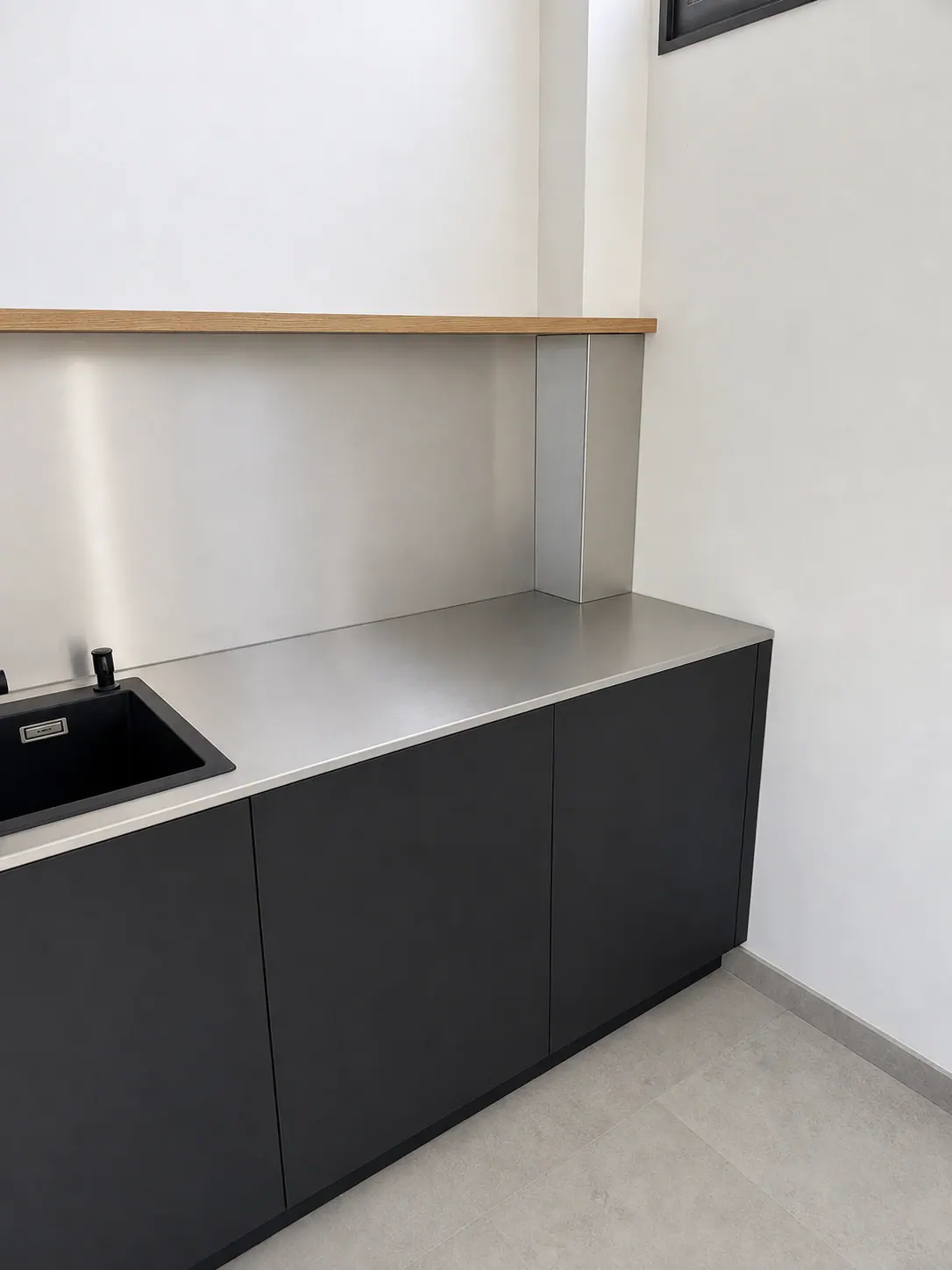 Cocina en negro con encimera de acero, vista a lo largo