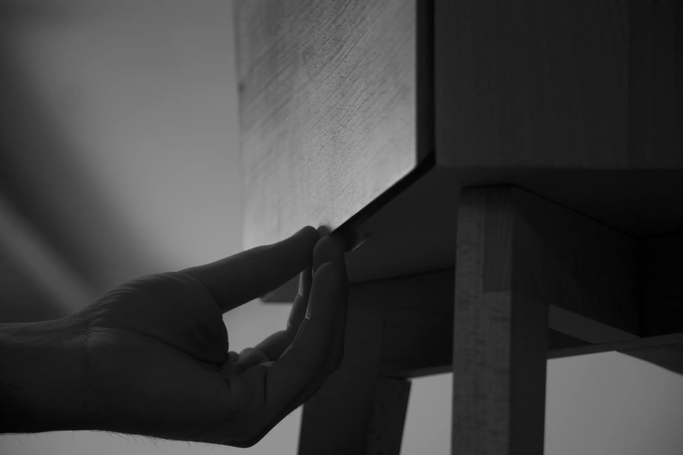 Mano apoyada sobre una mesa de noche de madera
