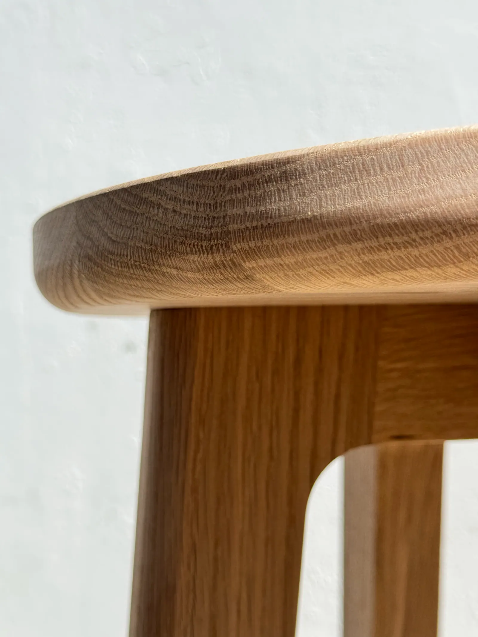 Detalle del asiento redondeado de un taburete de roble